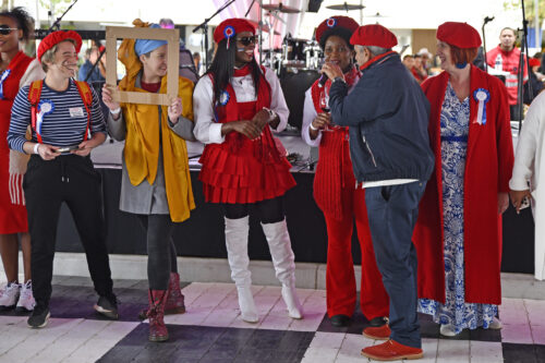 Group of people dressed in red and white, one holding a cardboard frame during the Best Dressed Competition