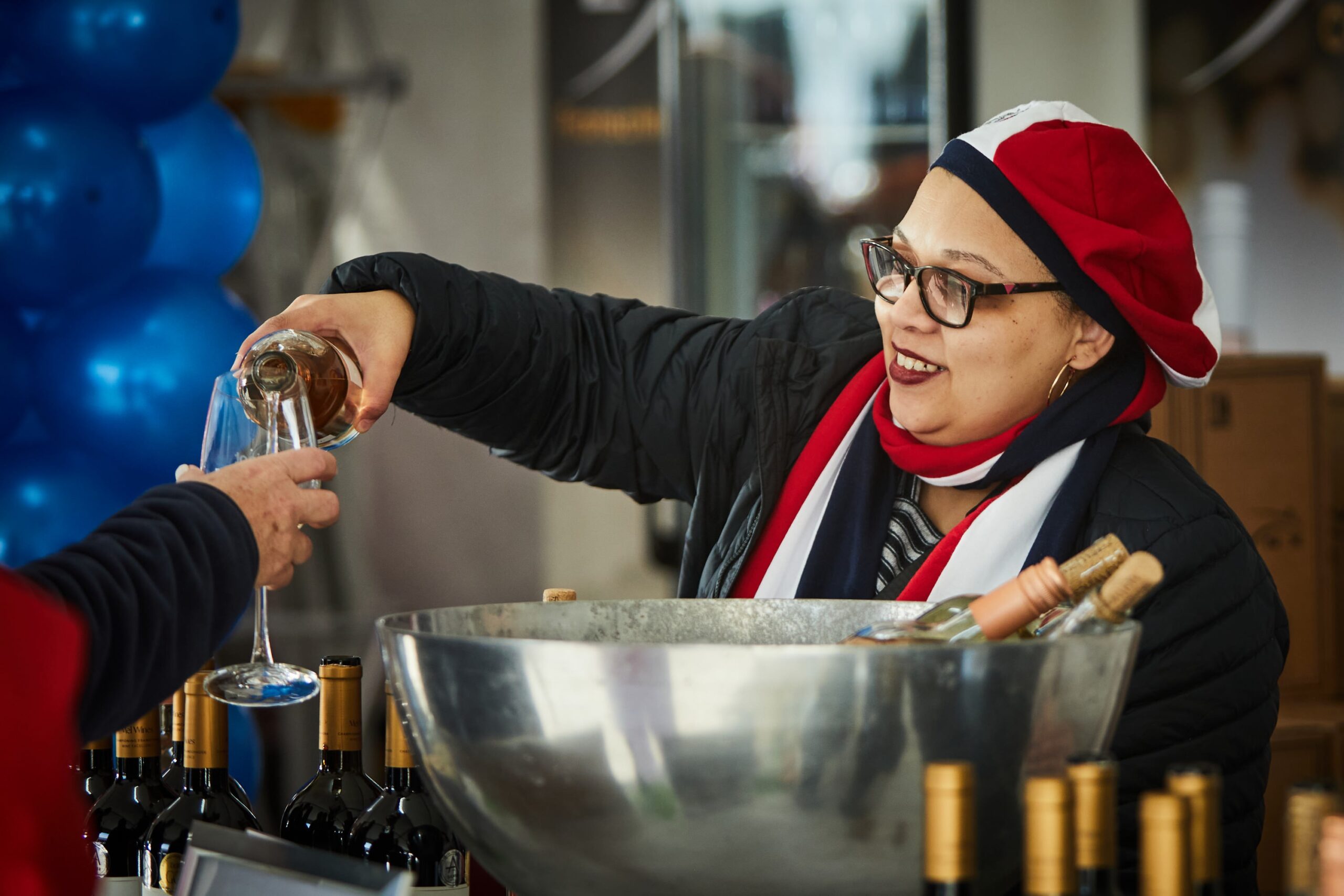 Woman in red, white, and blue pouring wine at the Iconic Franschhoek Bastille Festival