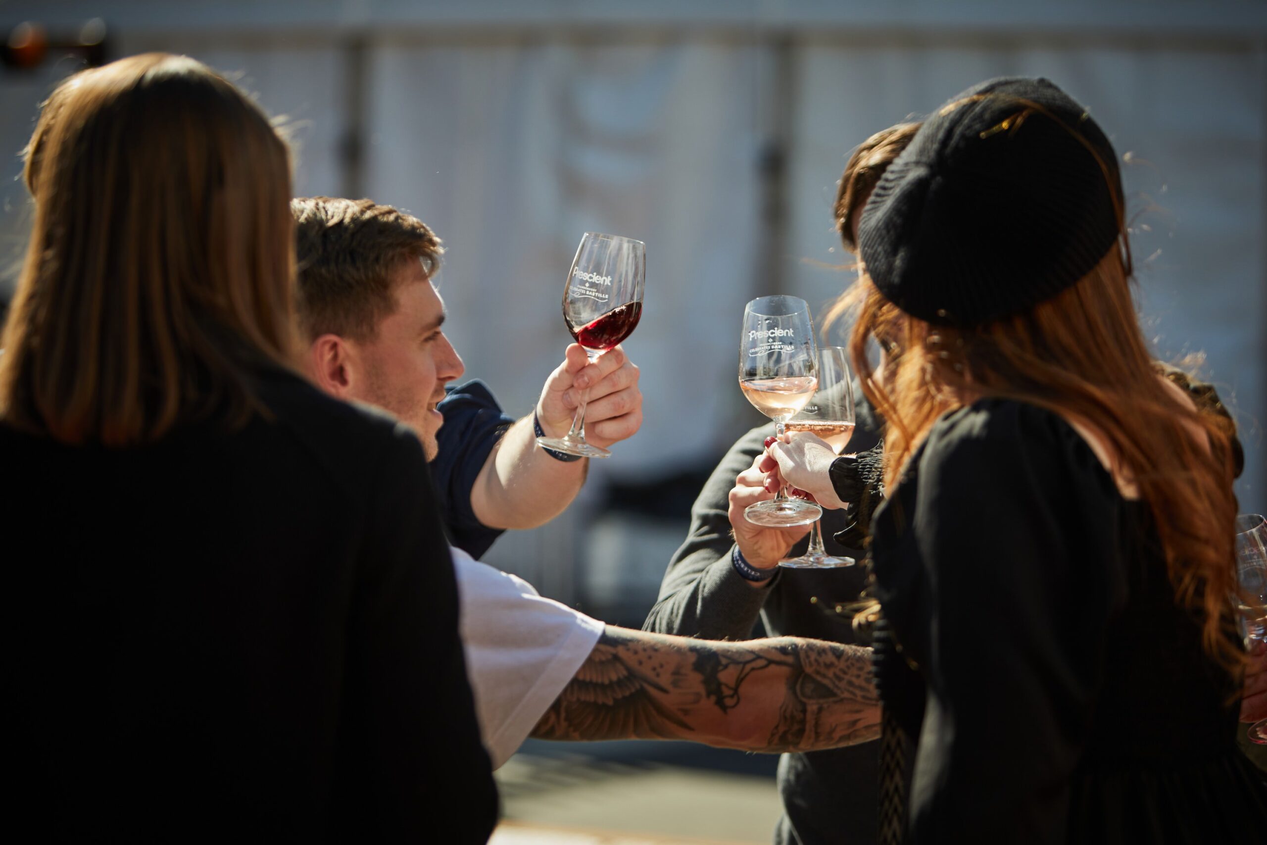 Friends clinking wine glasses with a vineyard logo visible on the glasses