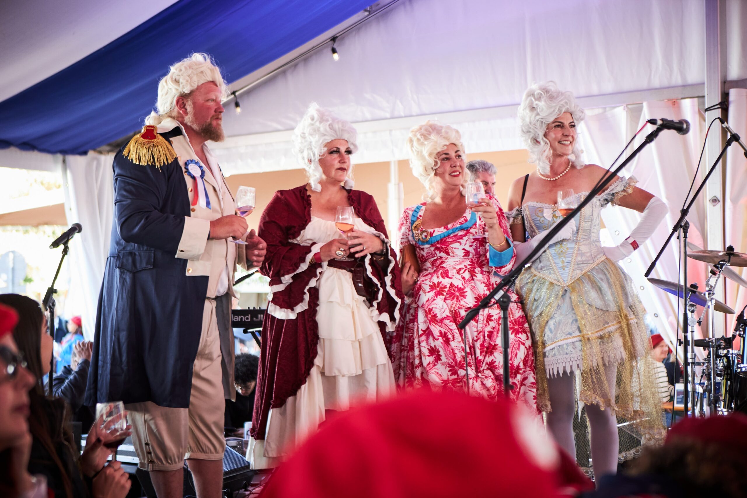 Four people in historical costumes, two women with elaborate wigs, a man in a military-style coat.