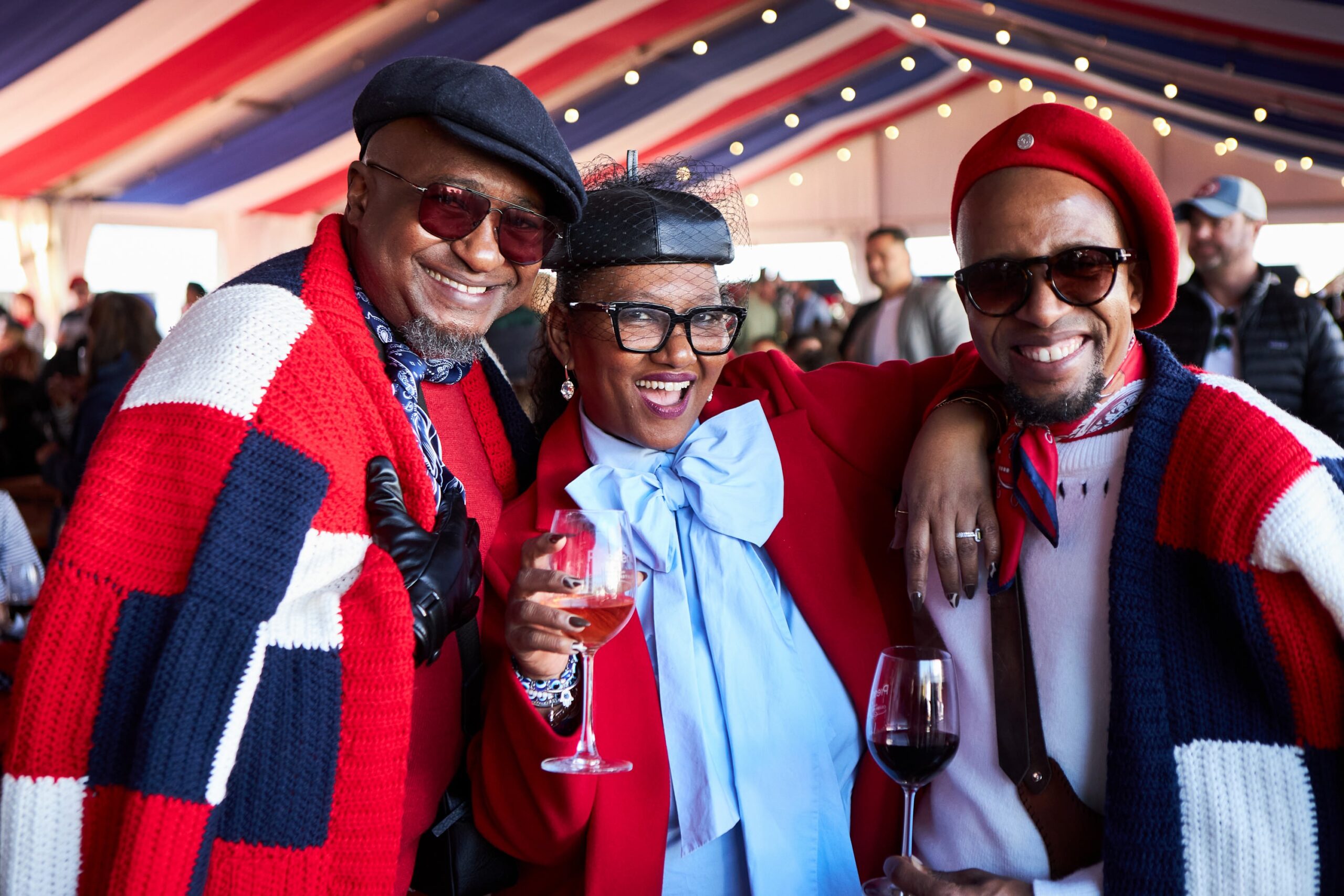 Three stylish individuals in red, white, and blue attire posing with wine glasses.